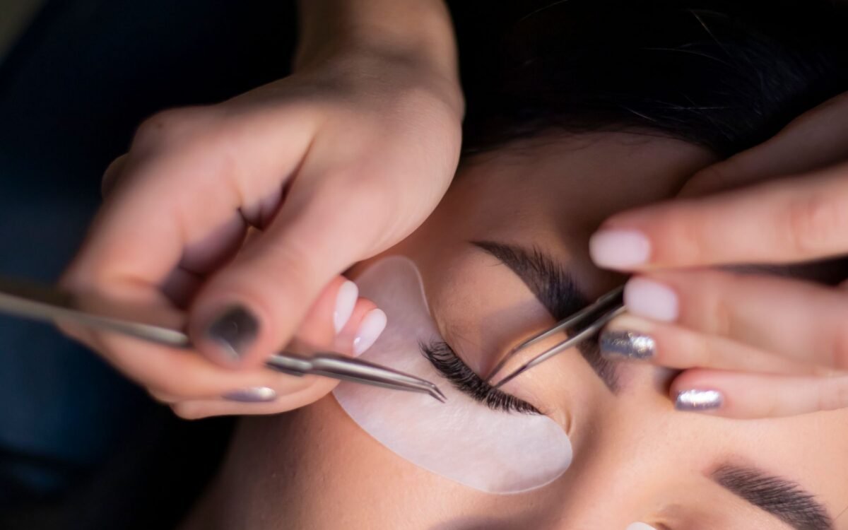 Visão detalhada de uma esteticista aplicando extensões de cílios nos olhos de uma mulher