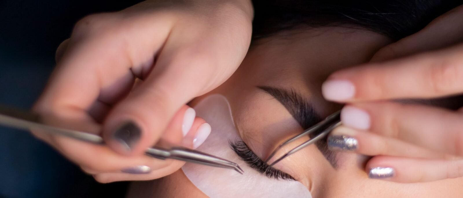 Visão detalhada de uma esteticista aplicando extensões de cílios nos olhos de uma mulher